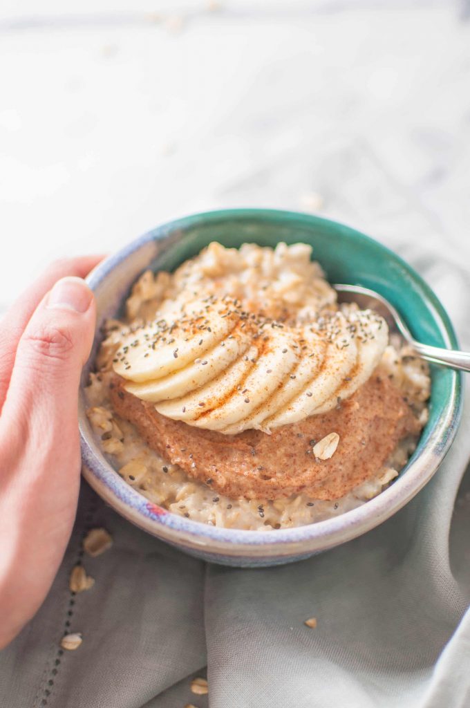 holding oatmeal with peanut butter and bananas on top