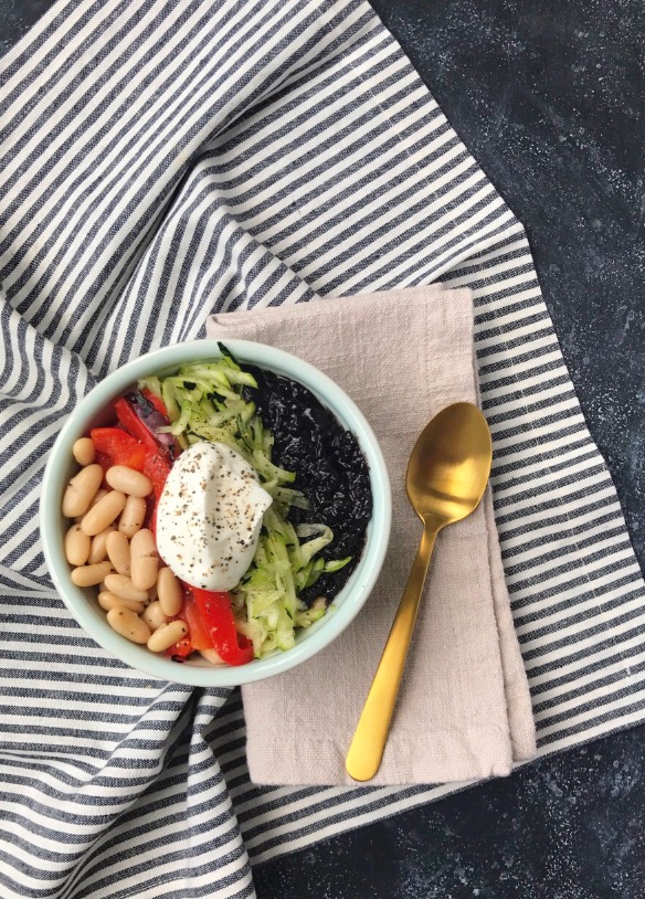Black Rice and Cannellini Bean Buddha Bowl on striped towel with gold spoon