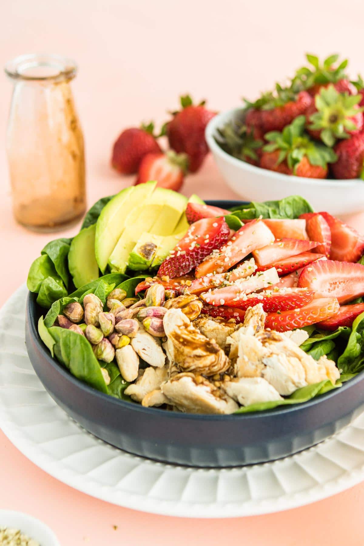easy strawberry salad in a blue bowl with ingredients in the background