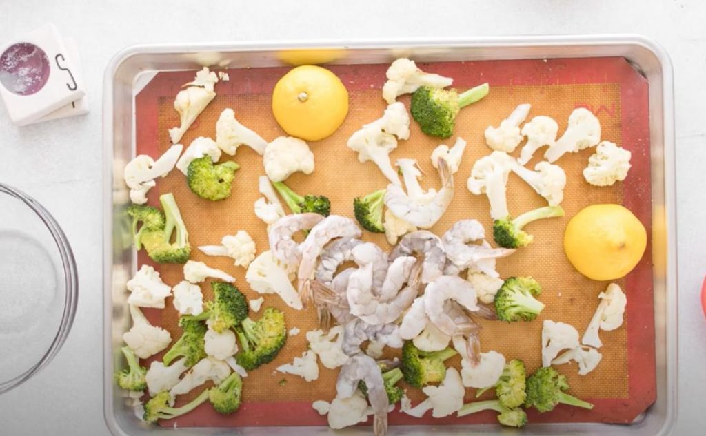cauliflower, broccoli, lemon wedges, and shrimp on a sheet pan