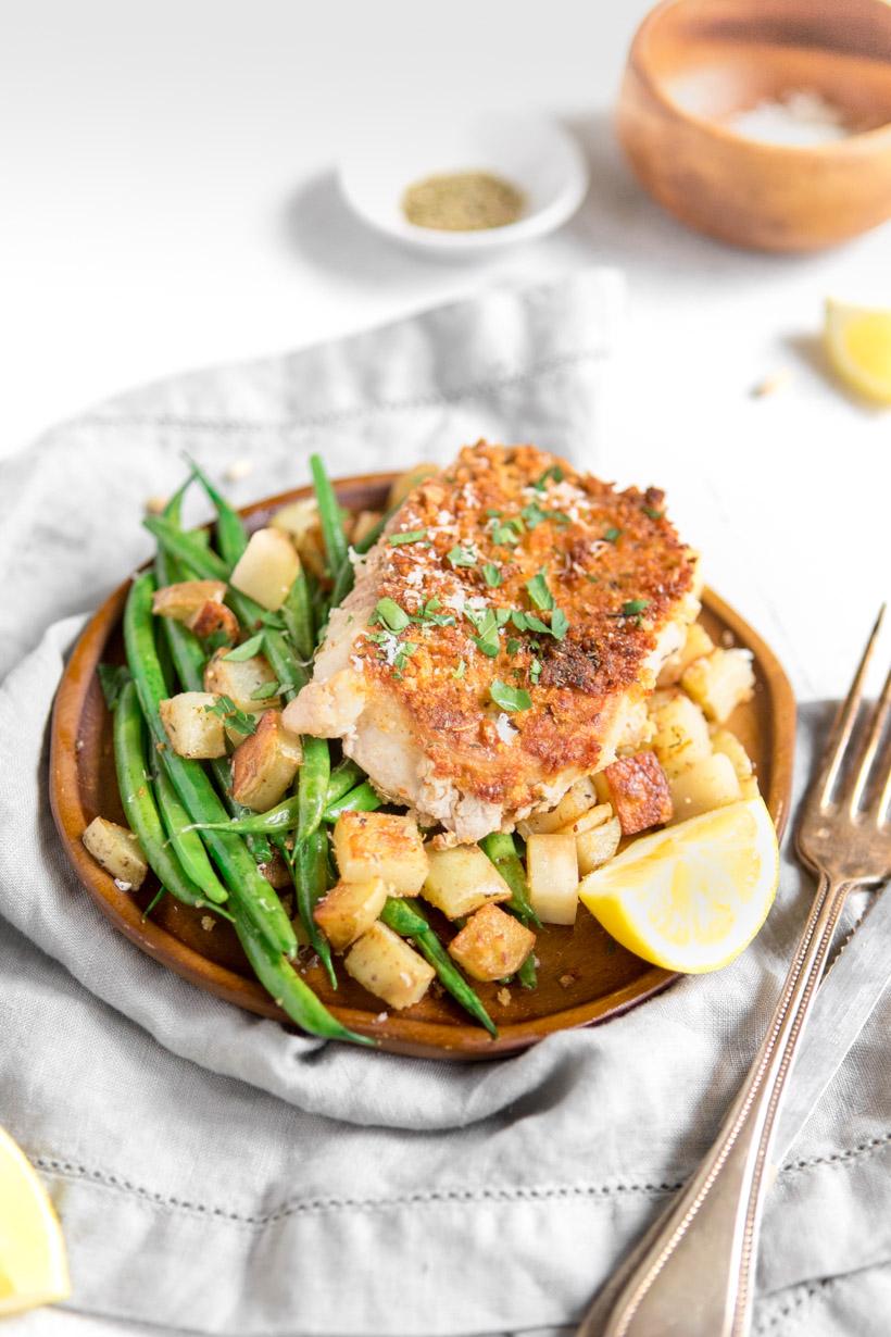 Pan seared pork chops with green beans and potatoes on a brown plate