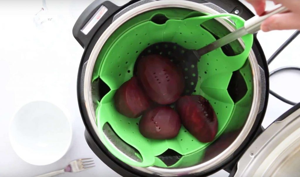 four beets in a green silicone steamer basket in an instant pot