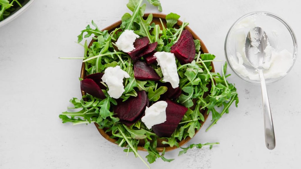 arugula, beets, and goat cheese for a beet and arugula salad on a plate