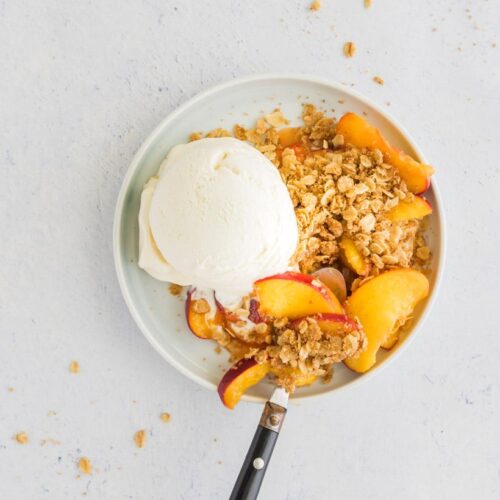 peach crumble in a bowl with ice cream