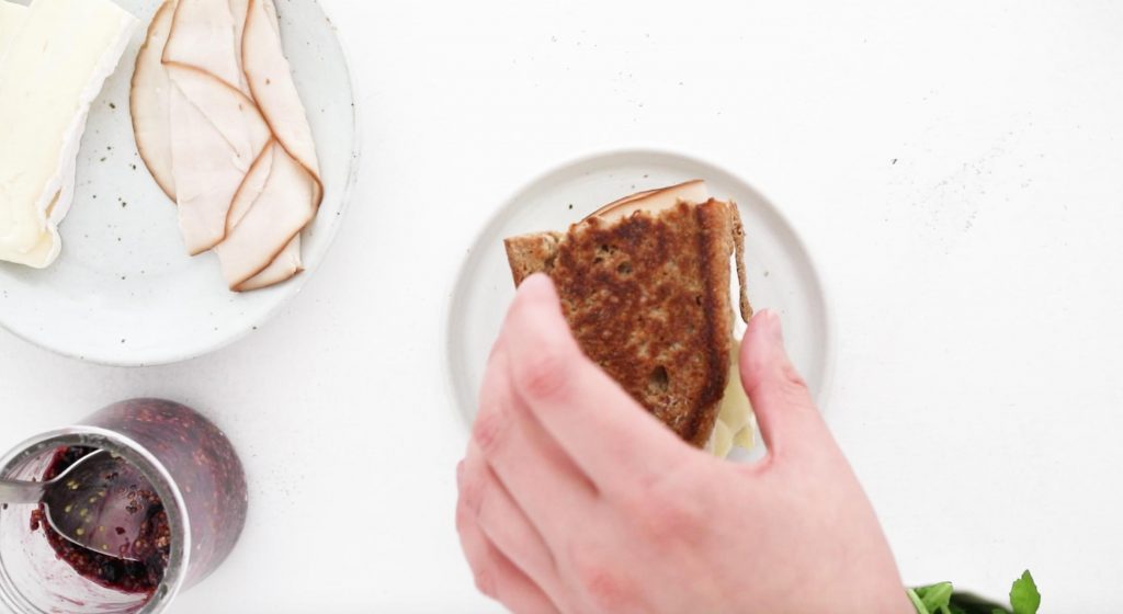 placing a slice of grilled bread on a sandwich