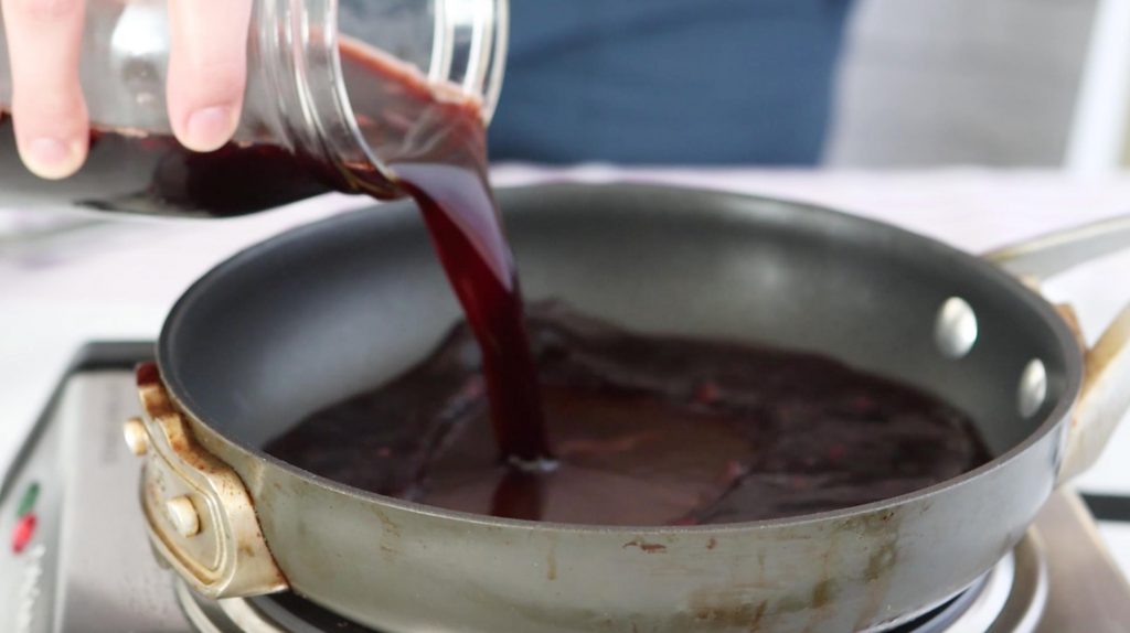 pouring pomegranate balsamic vinegar into saucepan