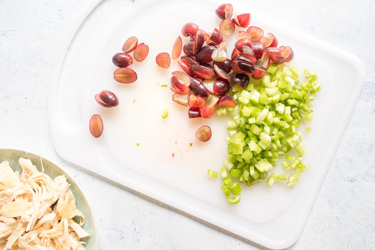 chopped celery and red grapes on a cutting board