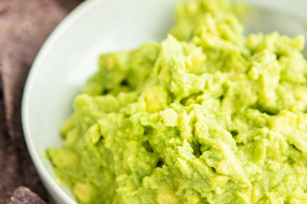 close up of healthy guacamole in a white bowl