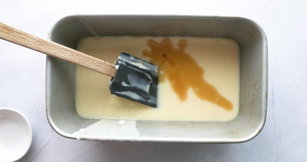 sweetened condensed milk and vanilla in a loaf pan with spatula in it