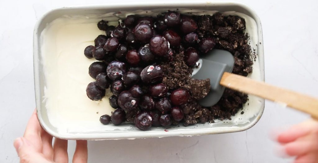 blueberries and oreos on top of ice cream in a loaf pan