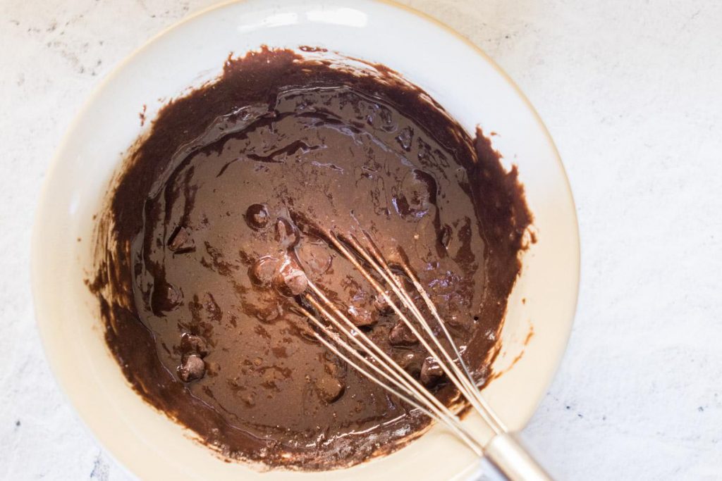 brownie batter in a mixing bowl with whisk in it