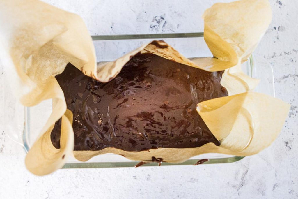brownie batter in a loaf pan with parchment paper